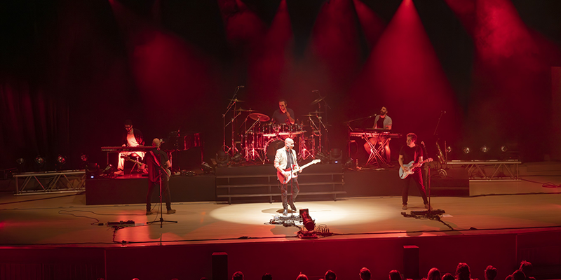 alt="La banda Brothers in Band interpretando éxitos de Dire Straits en el Auditorio de Torrevieja, bajo luces rojas y ambiente de directo"
