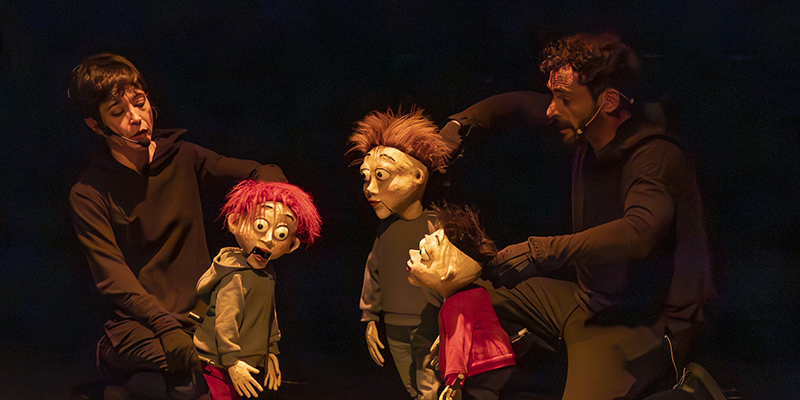 Escena de la obra 'La bruja rechinadientes' con los tres hermanos protagonistas y los manipuladores de títeres durante la representación en el Centro Cultural Virgen del Carmen