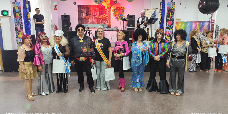va3410-semana-mayor1 alt=“Participantes disfrazados con estética de los años 70 en la fiesta temática celebrada en el Centro Polivalente de La Mata durante la Semana del Mayor en Torrevieja.”