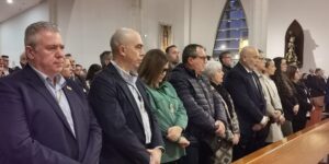 Fieles y miembros de las cofradías escuchando la misa en los bancos de la iglesia