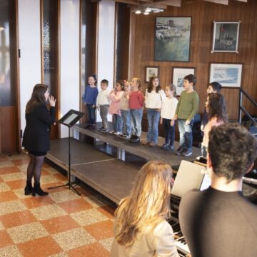 Niños y niñas de un coro infantil cantando en un escenario