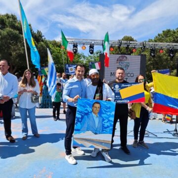 Personas de diversos países sujetando banderas al lado de Eduardo Dolón durante el Mosaico Fest de Torrevieja