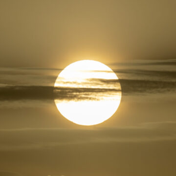 Nubes escasas de agua en frente del sol en el cielo