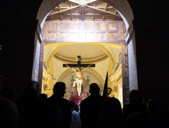 Fieles contemplando la imagen del Cristo Crucificado desde el umbral de la Iglesia