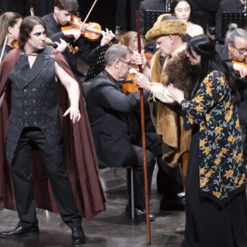 Varios personajes siendo representados en el escenario junto a la banda