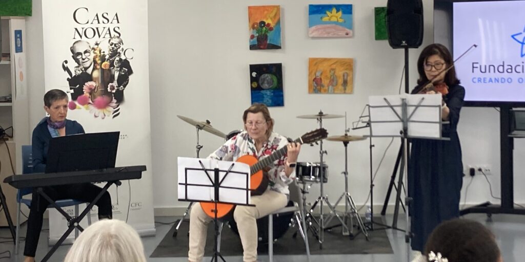 Tres músicas del curso interpretan sus piezas al piano, la guitarra y el violín como parte del variado repertorio ofrecido a los usuarios y trabajadores de ADIEM