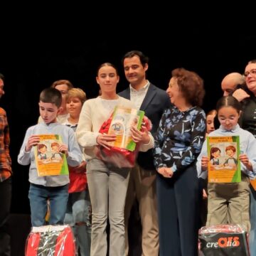 Jóvenes ganadores del vigésimo concurso infantil de cuentos mostrando sus libros y obsequios junto a las autoridades en el escenario del Centro Cultural Virgen del Carmen