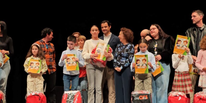 Jóvenes ganadores del vigésimo concurso infantil de cuentos mostrando sus libros y obsequios junto a las autoridades en el escenario del Centro Cultural Virgen del Carmen