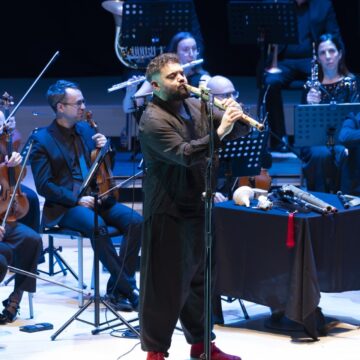 Abraham Cupeiro interpreta una melodía con un instrumento ancestral durante su espectáculo "PANGEA" en el Auditorio Internacional de Torrevieja, acompañado por una sección de orquesta
