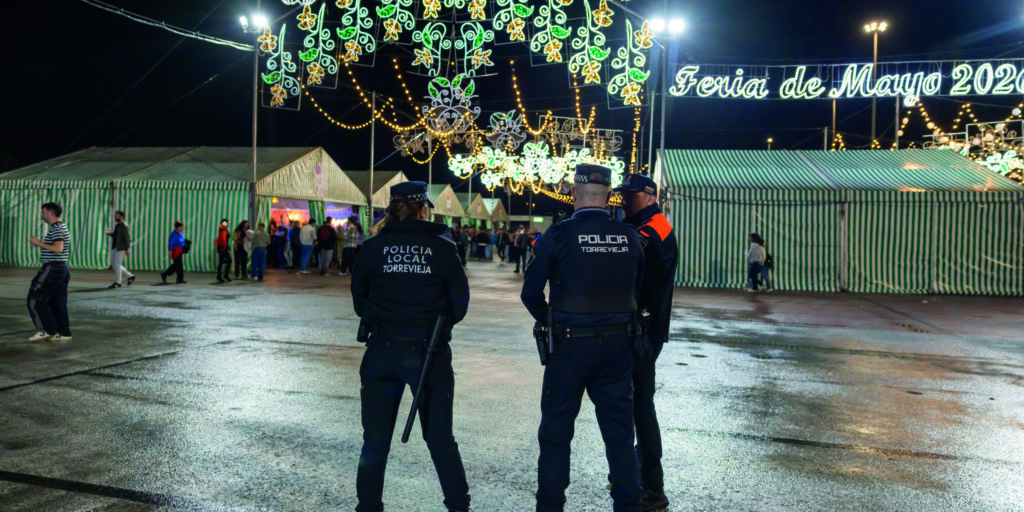 Agentes de la Policía Local de Torrevieja vigilan el recinto del Parque Antonio Soria bajo el alumbrado de la Feria de Mayo tras las lluvias registradas