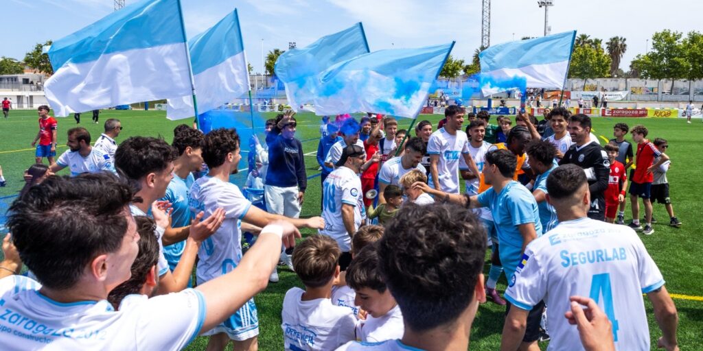 Aficionados y jugadores celebran en el césped con banderas y humo azul la clasificación matemática para la fase de ascenso