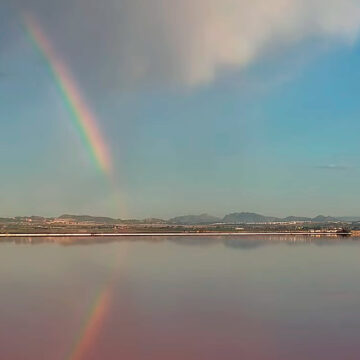 Arcoíris sobre la Laguna Rosa de Torrevieja bajo un cielo parcialmente nuboso.