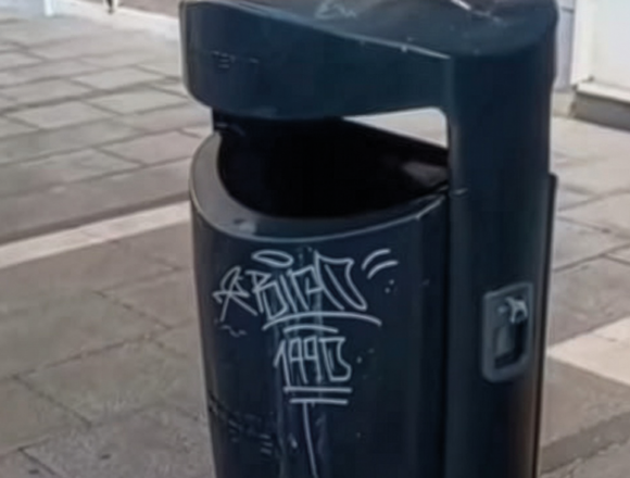 Papelera del mobiliario urbano de Torrevieja con pintadas vandálicas antes de los trabajos municipales de limpieza.